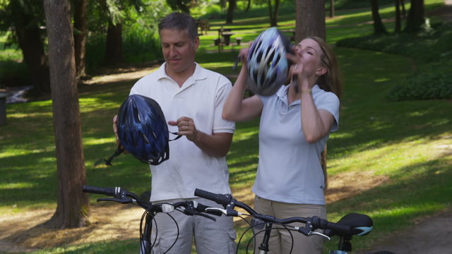Mature couple putting on bicycle helmets