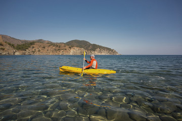 Men travel by canoe on the sea in the summer.