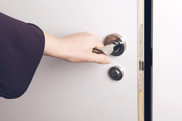 Naklejka premium Woman hand opens a door to a dark and unknown room.