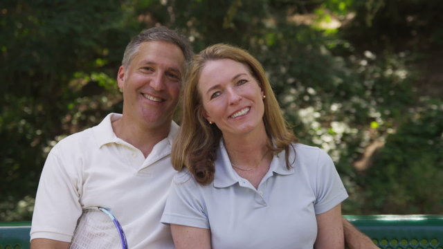 Portrait of mature couple outdoors with tennis racquets