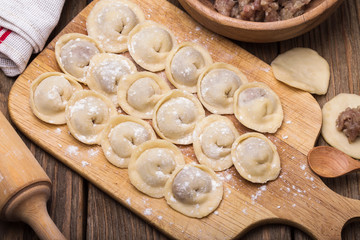 Fototapeta na wymiar Homemade meat dumplings - russian pelmeni on a wooden board