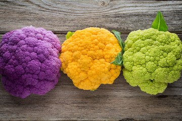 Rainbow of eco cauliflower on the wooden table.