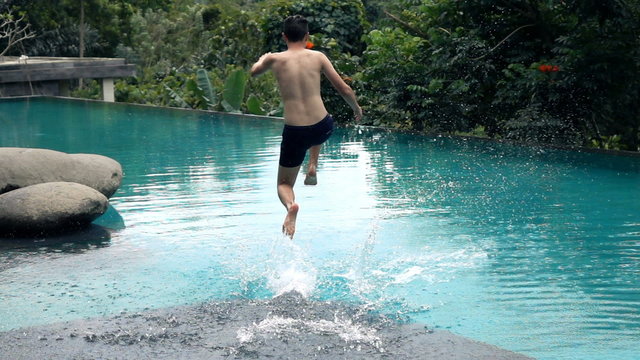 Young boy jumping into swimming pool, super slow motion 240fps
