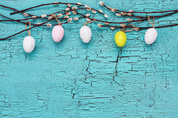 Easter background. Willow branch and Easter eggs on blue background. Copy space, top view.
