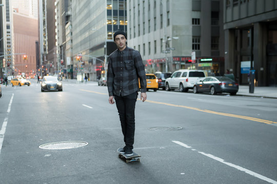 Young skateboarder cruise donw the city street before sunset