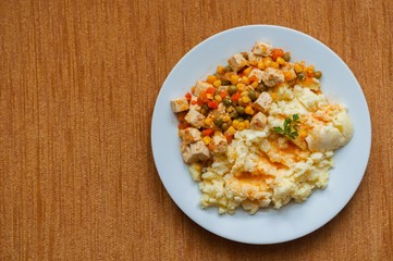Healthy vegetarian cuisine with tofu with colorful roast vegetables including carrot, peas and maize served with mashed potatoes. Top view