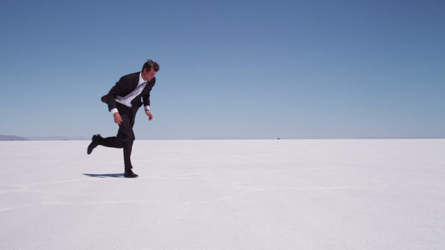 Businessman running at salt flat, slow motion