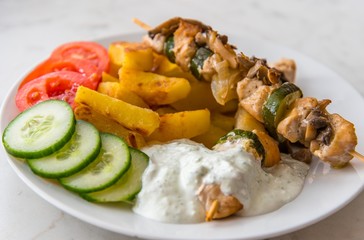 Traditional delicious chicken shish kebab with mushrooms. Served with American potatos, cucumber, tomatoes and tzatziki dressing