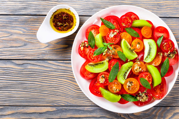 salad of yellow red and cherry tomatoes, kiwi fruit, mint