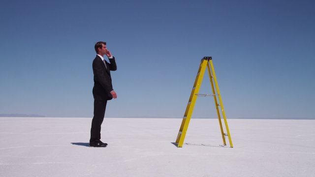 Businessman climbs a ladder trying to get cell phone reception