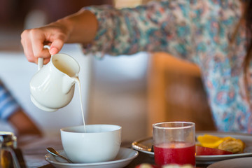 Woman pouring milk in mug from kettle
