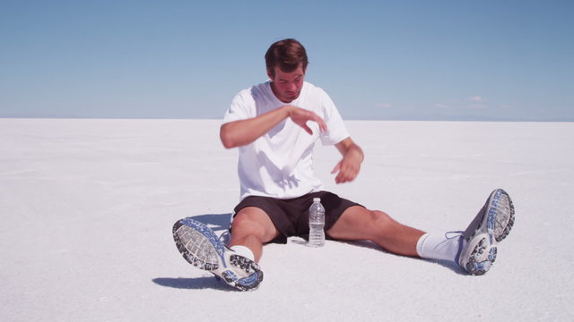Athlete sitting down drinking water at salt flat