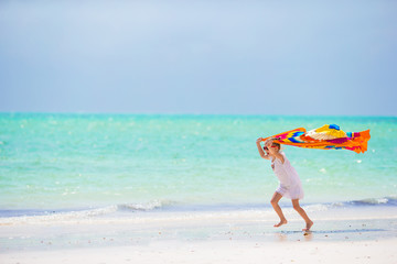 Obraz na płótnie Canvas Little girl having fun running with pareo on tropical beach 