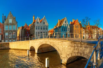 Fotobehang Toneelstadsmening van Brugs kanaal met mooie middeleeuwse gekleurde huizen en zonnige brug in de ochtend, gouden uur, België © Kavalenkava