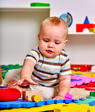 Kid baby boy lying on floor and plying with puzzle toy.  Early baby development.