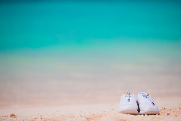 Fototapeta na wymiar Sport shoes on white sandy beach