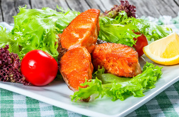 fried salmon with fresh salad, cherry tomato and lemon.