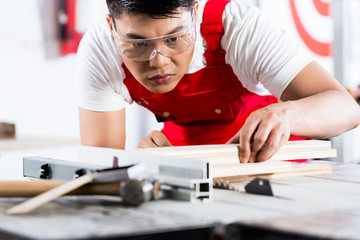 Asian Chinese Carpenter cutting wood with saw