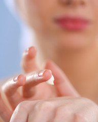 Young woman  putting cream on her hand Isolated on gray background