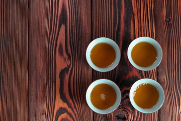 Mug of hot delicious green tea on wooden background. Delicious oriental beverage.