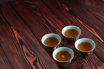 Mug of hot delicious green tea on wooden background. Delicious oriental beverage.