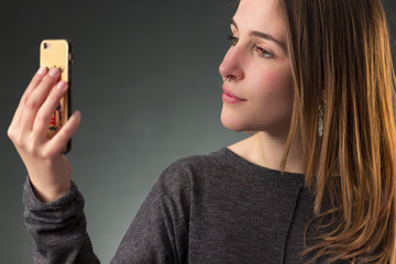 Blonde girl with nose ring is reading a message on her smartphone