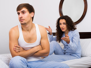 Upset husband and angry wife in bed