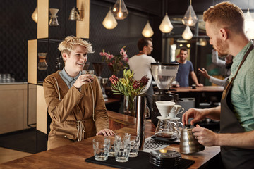 Young woman smiling while a barista makes some filter coffee