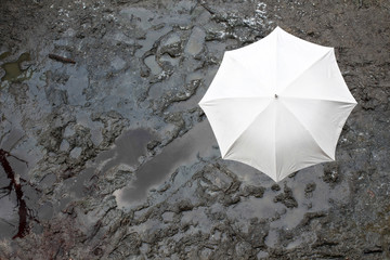 Positive white umbrella on a muddy ground in a rain weather