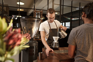Barista pouring coffee through filter in modern cafe