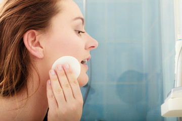 Woman removing makeup with cotton swab pad.