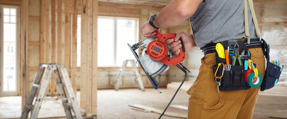 Hands of construction builder with electric saw.