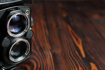 The lens of old film camera on a wooden table.