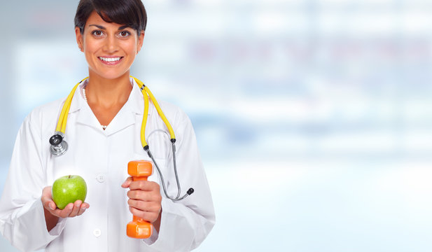 Doctor woman with dumbbell and apple.