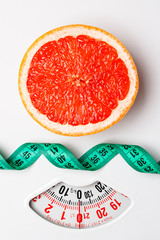 Grapefruit with measuring tape on weight scale. Dieting