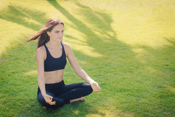 Молодая женщина занимается йогой на зеленом газоне