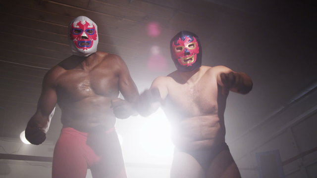 Two masked wrestlers intimidating opponent