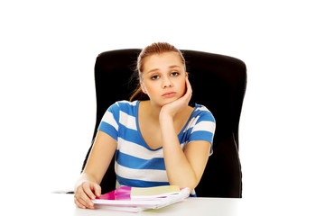 Tired teenage woman sitting behind the desk