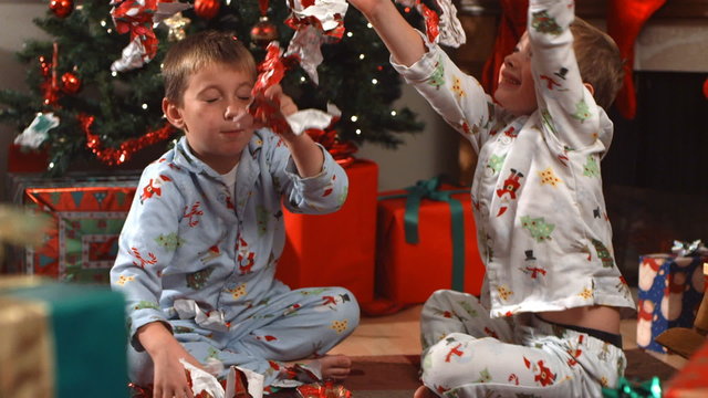 Young boys throw Christmas wrapping paper, slow motion