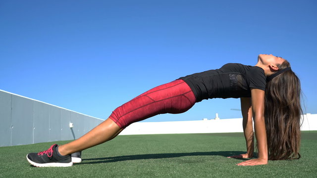 Yoga fitness woman stretching body in upward plank pose doing reverse planking exercise on outdoor grass. Sport woman strength training her core with bodyweight flexibility exercises.