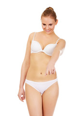 Obraz premium Young woman in white lingerie pointing for copyspace or something