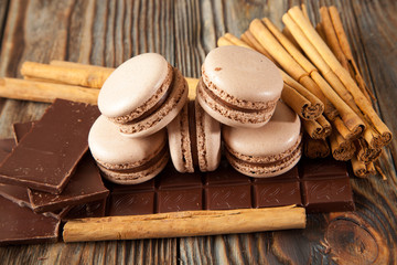 Chocolate macaroons and black chocolate on old wooden table