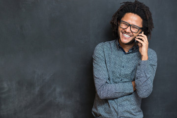 Typing message. Handsome young man with afro hair in shirt holdi