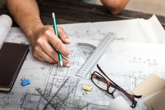 Close-up Of Person's Hand Drawing Plan On Blue Print with archit