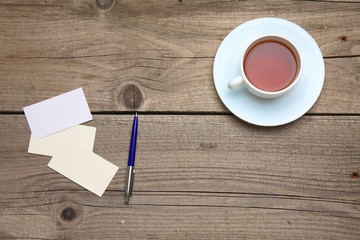 Obraz na płótnie Canvas Blank business cards with pen and tea cup on wooden office table