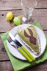  Easter decorations, knife and fork on plate on napkin on aged wooden background. Selective focus.