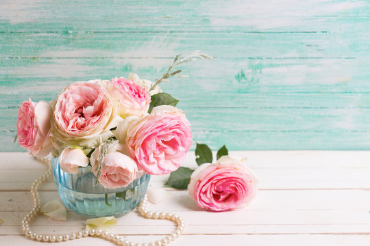 Pink roses flowers  in blue vase on white painted wooden backgro