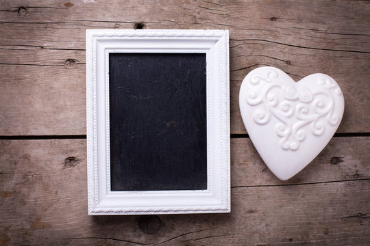 White  heart and empty blackboard on aged wooden background.