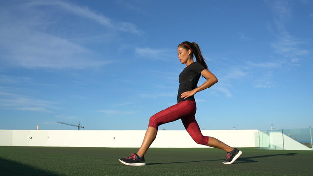 Lunges exercises woman doing front lunge leg exercise workout for quads, thighs and calves strength training. Fitness woman exercising outside on grass.