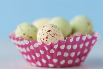 Closeup of chocolate speckled Easter eggs in a crisp sugar shell in cupcape liner. Shallow depth of field.